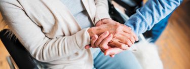 Person in wheel chair holding hand of another man