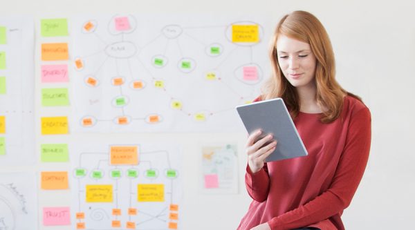 two business women standing side by side reading the agenda