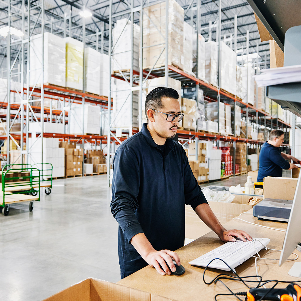 man standing in a warehouse using a computer