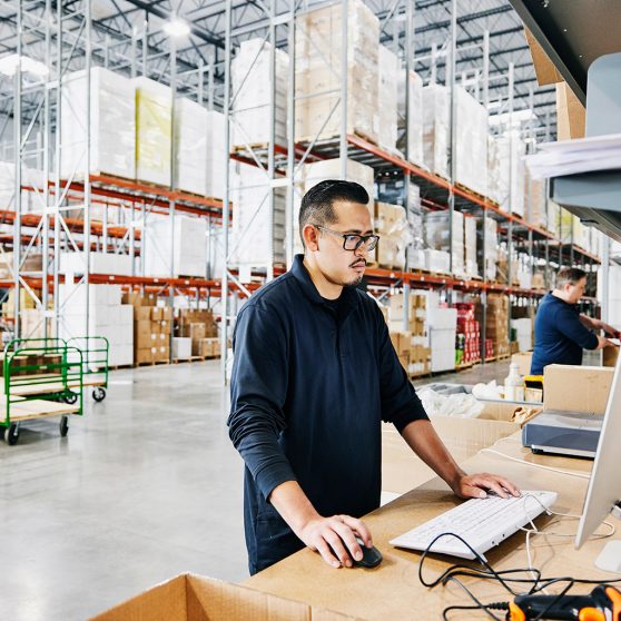 man standing in a warehouse using a computer