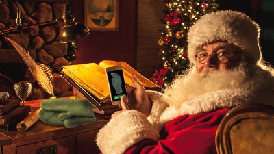 Santa in his office ordering gifts from a mobile device