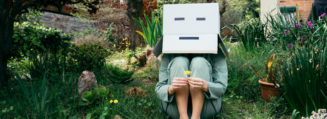 Person sitting in garden wearing a box on head