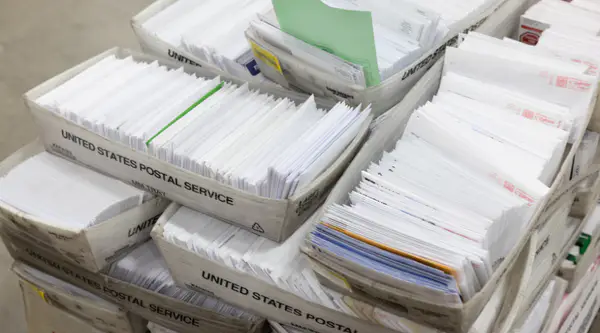 Stacks of envelopes in USPS containers