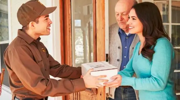 UPS worker handing a woman and older man a shipping package