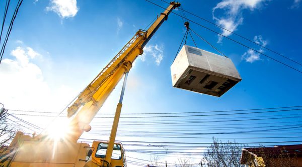 a yellow crane lifting a large piece of equipment 