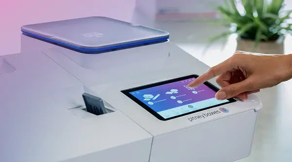 a finger touching the screen on a Pitney Bowes postage meter
