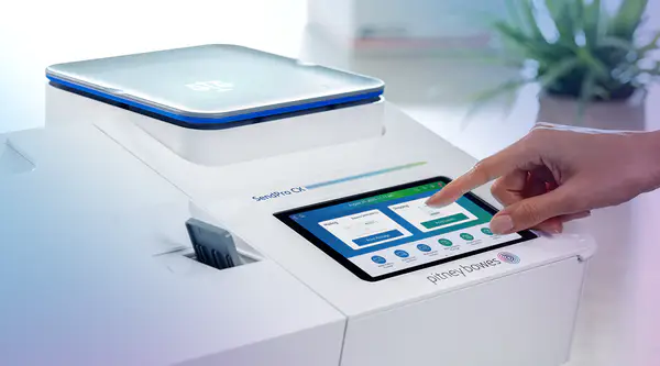 a finger touching the screen on a Pitney Bowes postage meter