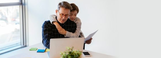 father and son staring at a screen in a home office
