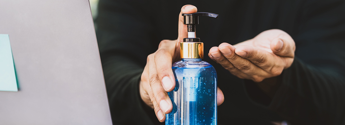 Hand sanitizer bottle with a hand ready to receive it